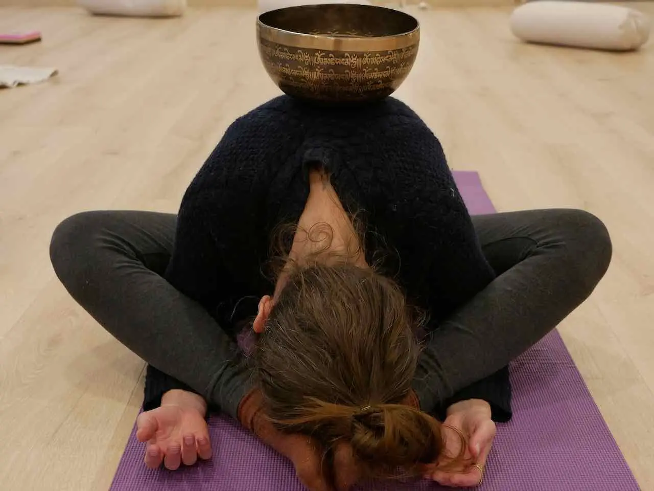 posture de yin yoga avec un bol tibetain pose sur le dos
