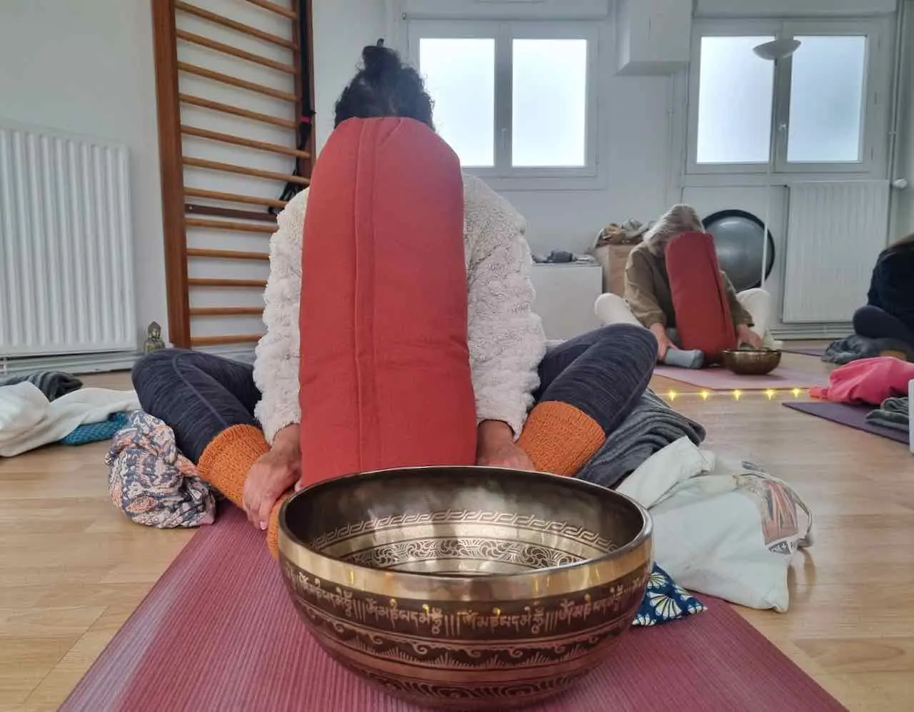 posture de yin yoga avec un bol tibetain place devant le participant